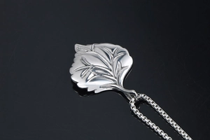 Macro shot of silver leaf pendant with detailed natural veins and polished finish