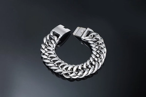 Macro detail of men's wide double-row curb chain bracelet in polished stainless steel
