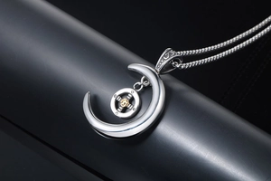 Vue détaillée du pendentif lune argentée avec soleil doré et gravures de style rétro