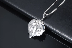 Detailed macro view of silver leaf pendant with intricate vein textures on box chain