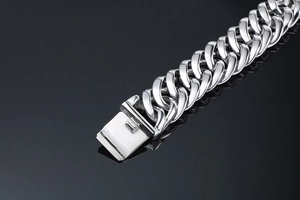 Macro view of men's wide stainless steel Cuban link bracelet with polished clasp details