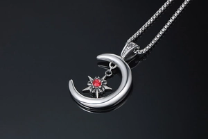 Détail du pendentif lune et étoile gothique avec zircon rouge sur chaîne sur fond noir