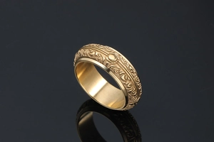 Close-up of vintage gold stainless steel ring with intricate baroque relief carvings