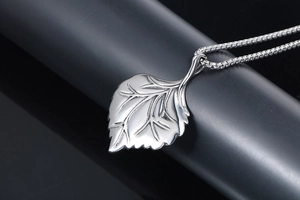 Macro shot of silver leaf pendant with detailed vein texture on a sleek box chain necklace