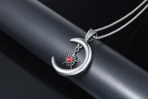Gros plan sur un pendentif croissant de lune et étoile argentée avec gemme rouge vif