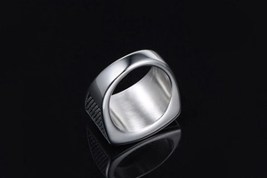 Detailed close-up of a silver signet ring with square polished top and side grid texture