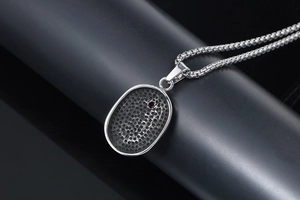 Macro detail of silver titanium pendant with honeycomb texture and tiny red ruby inlay