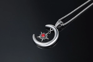Détail macro du pendentif croissant de lune et étoile avec pierre rouge sur chaîne
