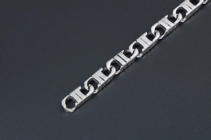 Close-up of polished silver metal geometric chain links with industrial interlocking design