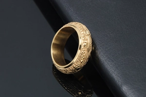 Macro shot of gold vintage titanium ring with baroque floral patterns on black background