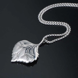 Polished silver leaf pendant necklace with realistic veins on black reflective surface