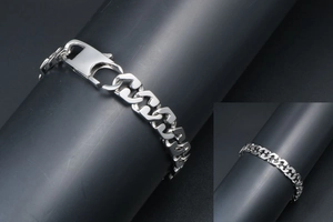 Macro detail of silver-tone cuban link bracelet with polished surface and lobster clasp