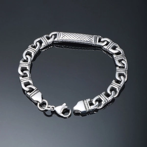 Men's punk stainless steel bracelet with textured plate on a dark reflective surface