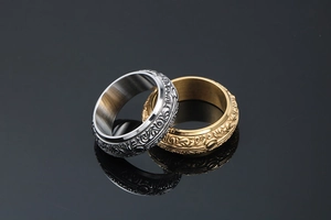 Detail of vintage embossed floral patterns on silver and gold wide titanium steel rings