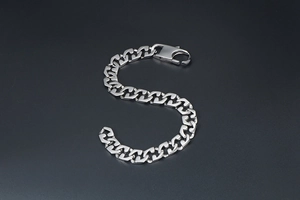 Close-up of polished silver titanium steel curb chain bracelet with lobster clasp