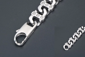 Vue macro d'un bracelet en acier titane argenté avec maillons en S et fermoir homard