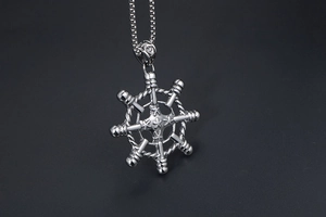 Macro detail of nautical ship wheel pendant in silver steel with star relief and o-chain