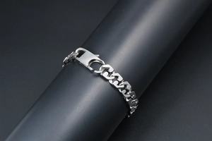 Close-up of polished silver steel flat curb chain bracelet with large lobster clasp