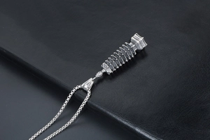 Dettaglio del ciondolo a pagoda vintage in argento con rilievo su pelle nera