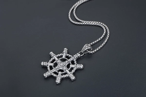 Macro view of vintage silver nautical ship wheel pendant with detailed rope texture and box chain