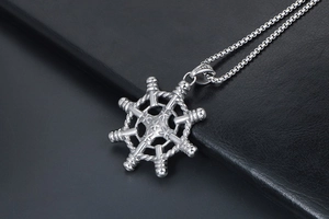 Macro shot of silver ship wheel pendant with S925 stamp on black leather background