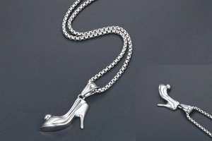 Macro detail of high heel shoe pendant with polished silver-tone finish on a box chain