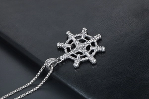 Macro view of silver rudder pendant with rope texture on black leather background