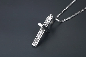 Vue macro d'un pendentif croix argenté vintage avec textures et chaîne box
