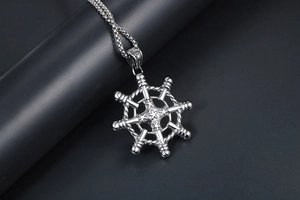 Detailed close-up of a silver nautical ship wheel pendant with vintage engraved patterns