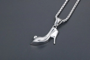 Macro view of a silver high heel shoe pendant necklace on a dark textured background