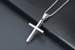 Vue détaillée d'un pendentif croix en acier poli avec côtés texturés et chaîne ronde