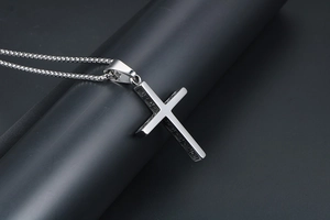 Détail macro du pendentif croix en acier titane argenté avec gravures internes