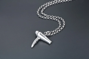 Détail du pendentif sèche-cheveux argenté avec poignée texturée sur une chaîne en acier