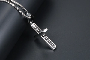 Gros plan d'un pendentif croix en acier titane vintage avec détails en relief et chaîne