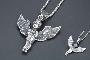 Macro detail of silver angel prayer pendant showing vintage texture and box chain