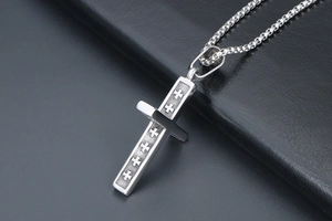 Gros plan du pendentif croix en titane argenté avec détails gravés sur cuir noir
