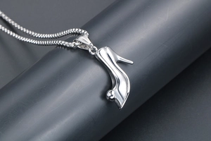 Macro shot of polished silver high heel pendant with ball detail and round box chain necklace