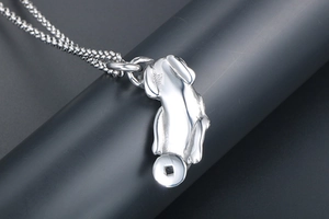 Macro shot of silver bulldog pendant with coin and woven chain on a jewelry stand