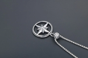 Detail shot of a silver star compass pendant with rope texture on a steel box chain