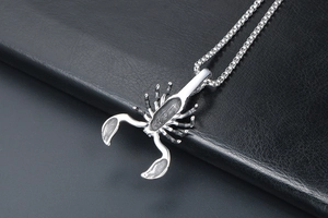 Polished silver scorpion pendant on a black leather pad showing gothic punk style details
