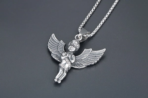 Macro shot of silver vintage angel pendant with embossed relief wings and box chain