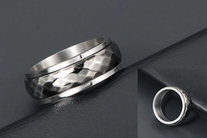 Macro detail of a silver spinner ring with textured diamond facets on a black leather background