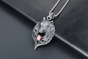 Close-up of vintage wolf head pendant with red zircon stone on black leather backdrop