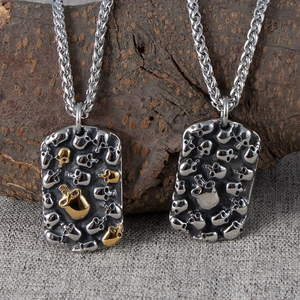 Detail of vintage punk skull tag pendant in silver and gold on a rugged tree bark background