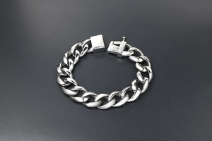 Detailed close-up of a silver-tone chunky cuban link chain bracelet with a square clasp