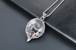 Close-up of vintage steel wolf head pendant with red gemstone and box chain