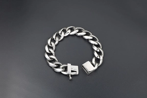 Detail of silver titanium steel cuban chain bracelet featuring a square safety clasp closure
