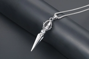 Detailed close-up of two-tone stainless steel lotus vajra pendant on a dark pedestal
