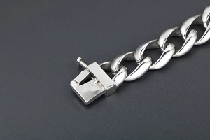 Detailed close-up of polished silver Cuban link bracelet with a secure box clasp mechanism