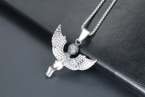 Macro shot of silver angel wing pendant and textured metal box chain over black leather